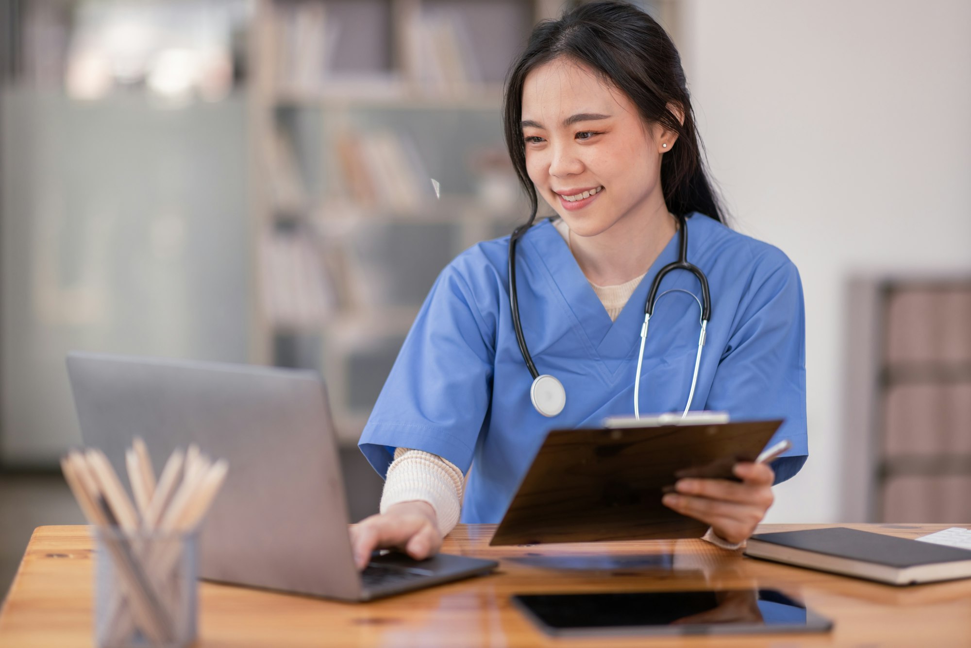 portrait of young asian smiling female nurse working on laptop in private clinic positive emotional 3.jpg